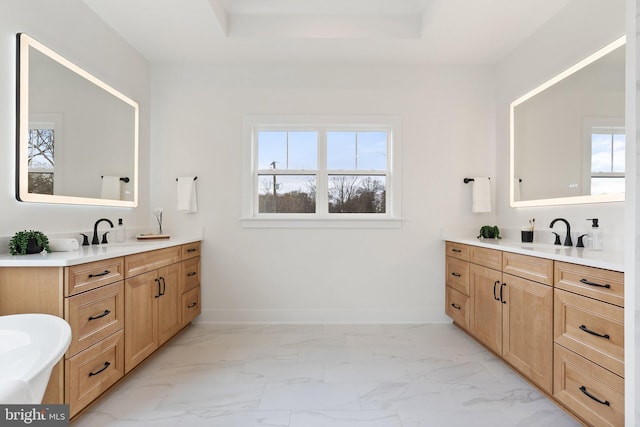 bathroom with marble finish floor, a healthy amount of sunlight, a sink, and baseboards