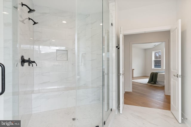 ensuite bathroom featuring connected bathroom, a shower stall, baseboards, and wood finished floors