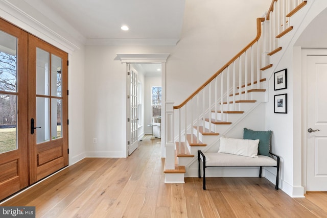 foyer with a healthy amount of sunlight, light wood-style floors, stairs, and french doors