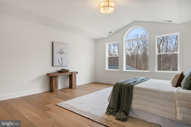 bedroom featuring lofted ceiling, baseboards, visible vents, and wood finished floors