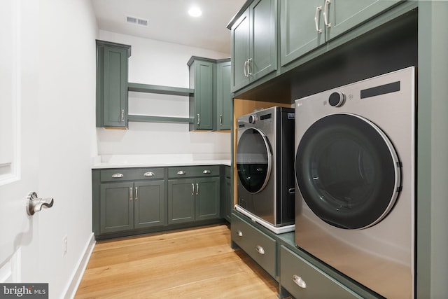 clothes washing area with visible vents, cabinet space, light wood-type flooring, independent washer and dryer, and baseboards