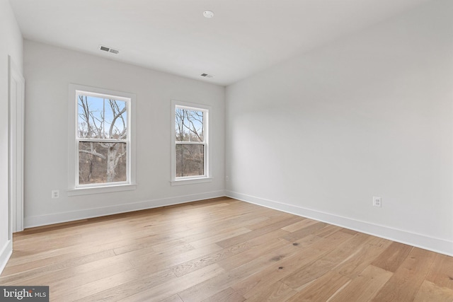 spare room with light wood-style floors, visible vents, and baseboards