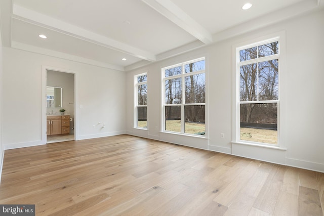 interior space featuring beam ceiling, a healthy amount of sunlight, light wood-style flooring, and baseboards