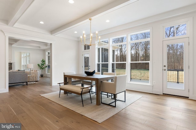 dining area with a healthy amount of sunlight, hardwood / wood-style flooring, a notable chandelier, and beam ceiling