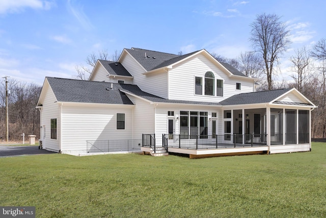 rear view of property with roof with shingles, a lawn, and a sunroom