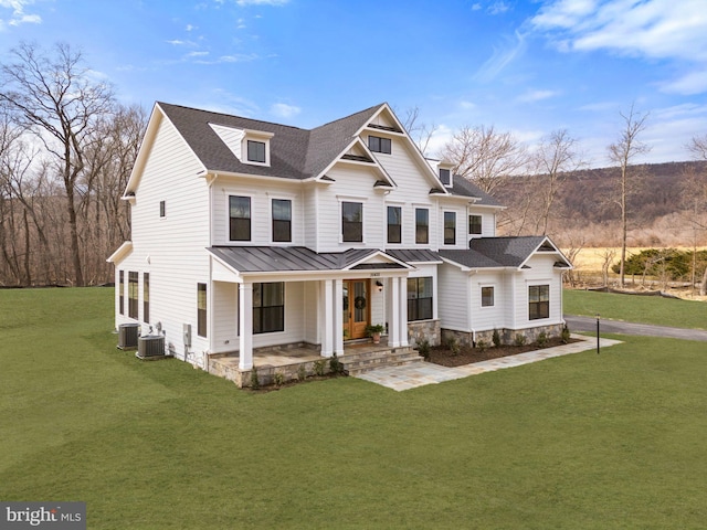 view of front of home with roof with shingles, central AC unit, a standing seam roof, metal roof, and a front lawn