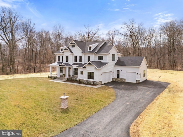 view of front of property with a front lawn, roof with shingles, an attached garage, and aphalt driveway