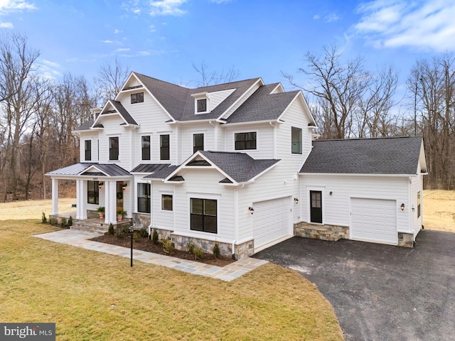 view of front of property with driveway, a garage, a shingled roof, metal roof, and a front lawn