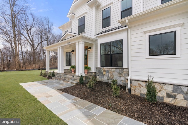 view of exterior entry with covered porch, a yard, and crawl space