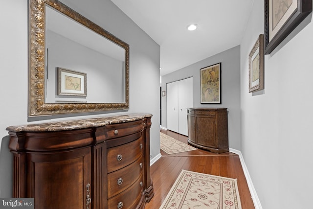 hallway with dark wood-style floors, baseboards, and recessed lighting