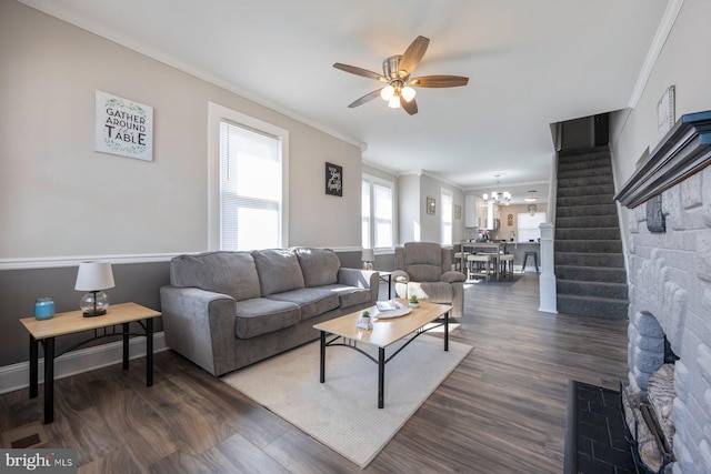 living room with ceiling fan with notable chandelier, dark wood-style floors, stairway, crown molding, and baseboards