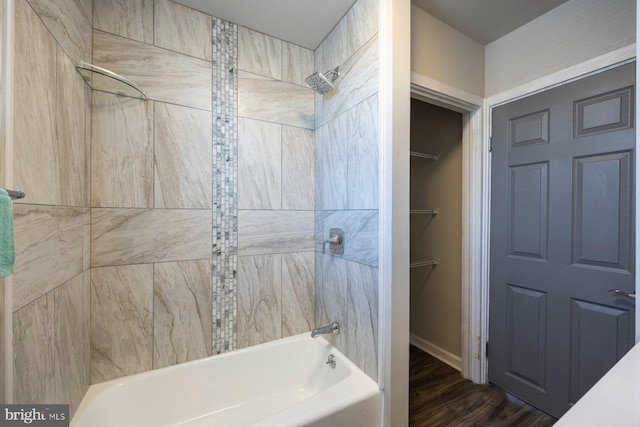 bathroom with a walk in closet, bathing tub / shower combination, and wood finished floors