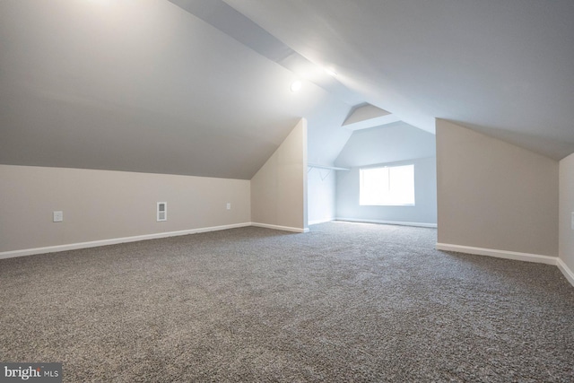 additional living space with visible vents, baseboards, lofted ceiling, and carpet floors