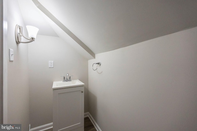 bathroom with baseboards, lofted ceiling, wood finished floors, and vanity