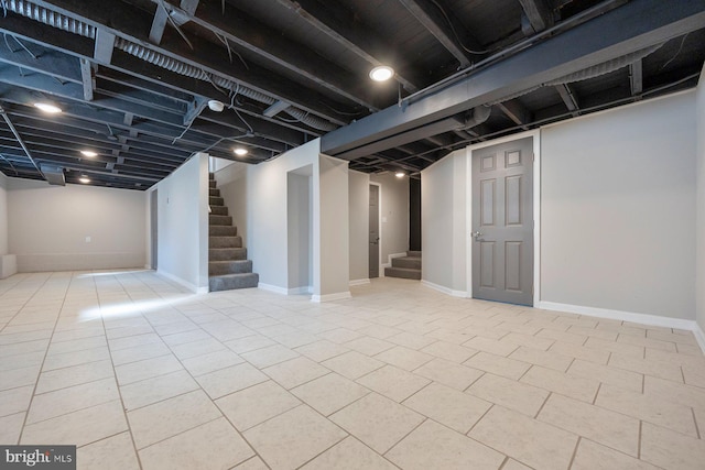 finished basement featuring tile patterned floors, stairway, and baseboards