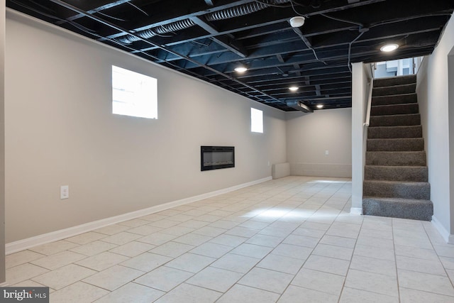 basement featuring light tile patterned floors, stairway, a wealth of natural light, and baseboards