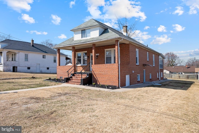 bungalow with a front lawn, brick siding, covered porch, and a shingled roof