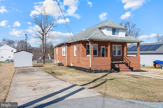 bungalow-style house with driveway, covered porch, a front yard, crawl space, and brick siding