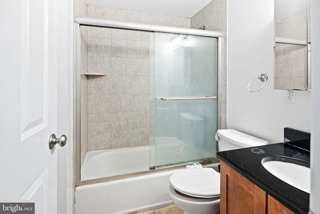 full bathroom featuring combined bath / shower with glass door, vanity, and toilet