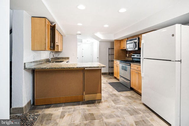 kitchen featuring stainless steel appliances, recessed lighting, a sink, light stone countertops, and a peninsula