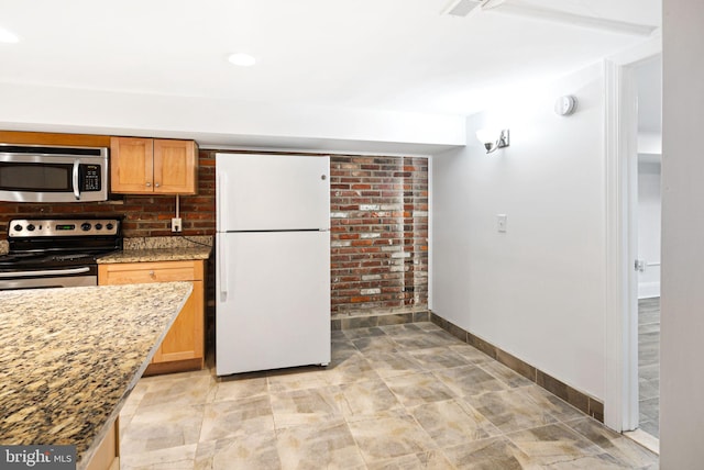 kitchen with appliances with stainless steel finishes, recessed lighting, light stone counters, and baseboards