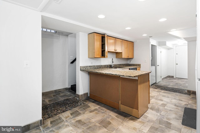 kitchen with recessed lighting, a sink, dark stone countertops, a peninsula, and baseboards