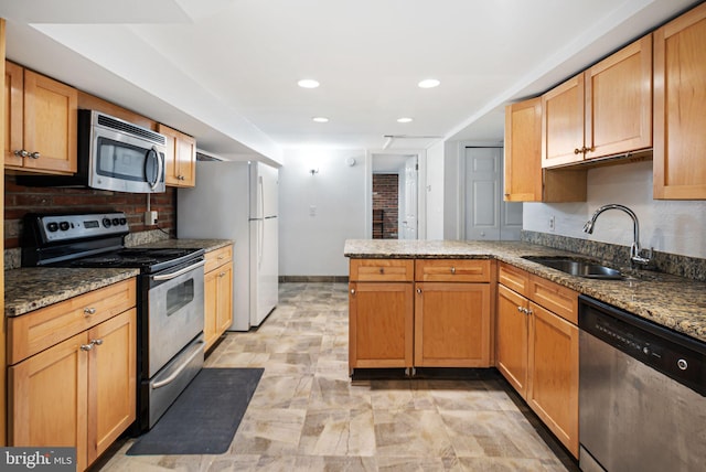 kitchen featuring stone countertops, baseboards, a peninsula, stainless steel appliances, and a sink