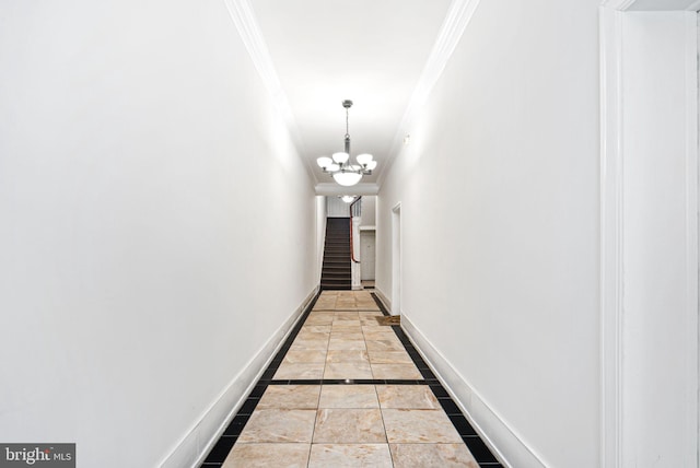 hall featuring a notable chandelier, ornamental molding, stairs, and baseboards