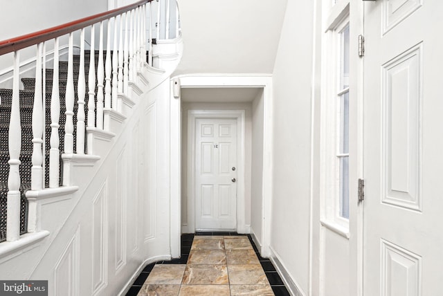 entryway with stone finish flooring, stairway, and baseboards