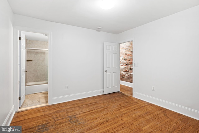 unfurnished bedroom featuring baseboards, wood finished floors, and ensuite bathroom