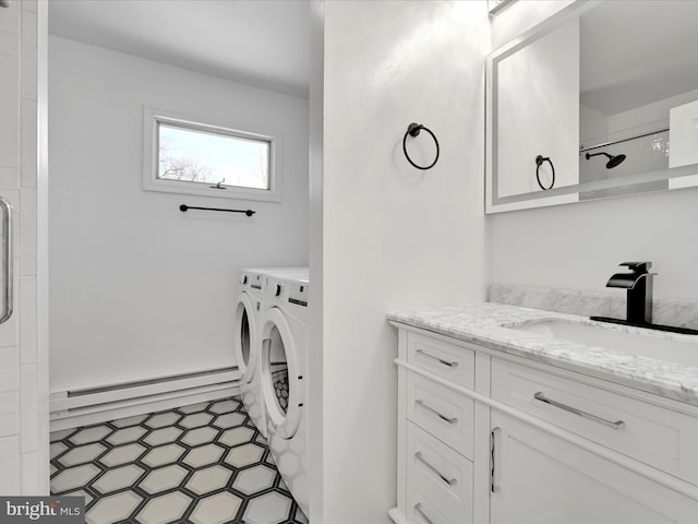 washroom featuring light floors, cabinet space, a baseboard heating unit, a sink, and washer and dryer