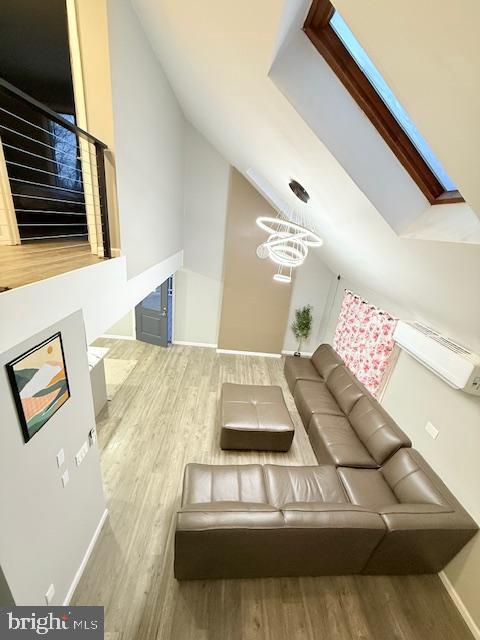 living room with lofted ceiling, a notable chandelier, baseboards, and wood finished floors