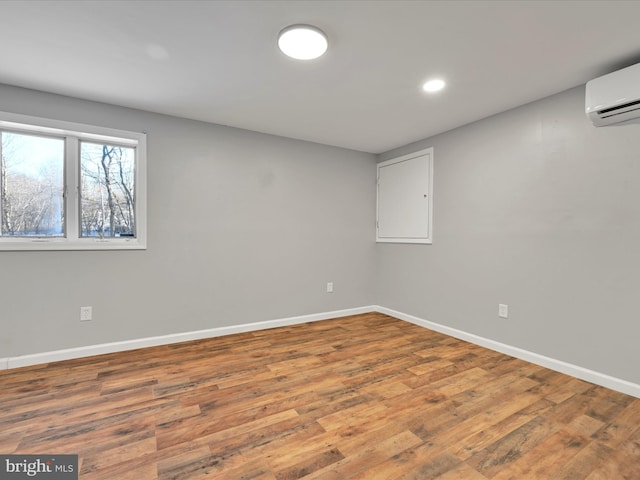 below grade area featuring recessed lighting, a wall mounted air conditioner, baseboards, and wood finished floors