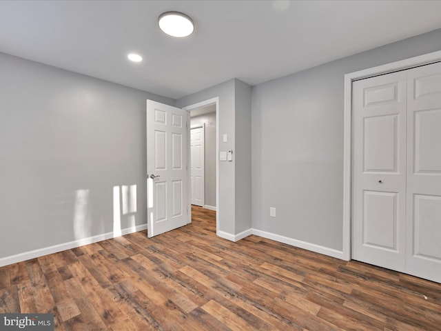 unfurnished bedroom with a closet, baseboards, and wood finished floors