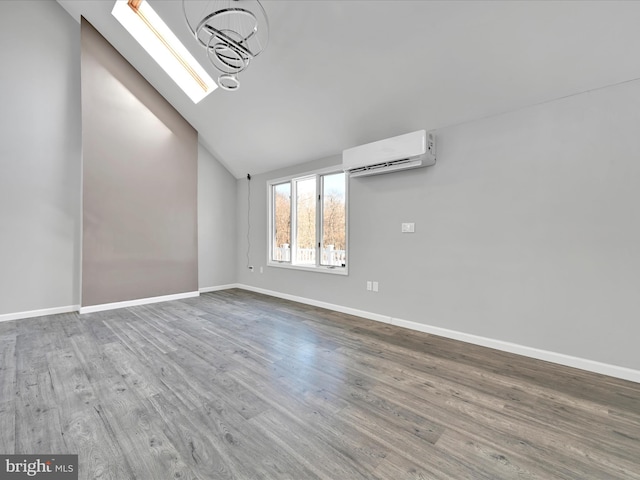 unfurnished room with a chandelier, wood finished floors, baseboards, lofted ceiling with skylight, and a wall mounted air conditioner