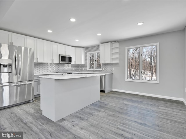 kitchen featuring light wood finished floors, open shelves, stainless steel appliances, decorative backsplash, and a kitchen island