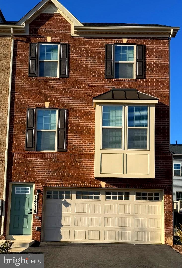 townhome / multi-family property featuring brick siding, driveway, and a garage