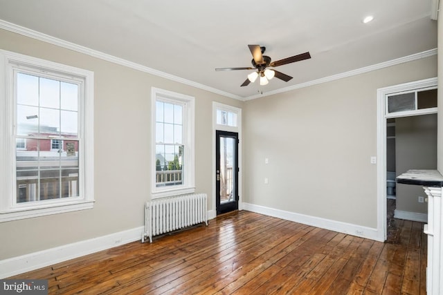 foyer entrance with radiator, wood-type flooring, baseboards, and crown molding