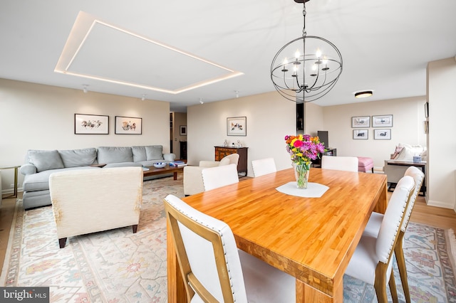 dining area featuring baseboards, a chandelier, and light wood finished floors