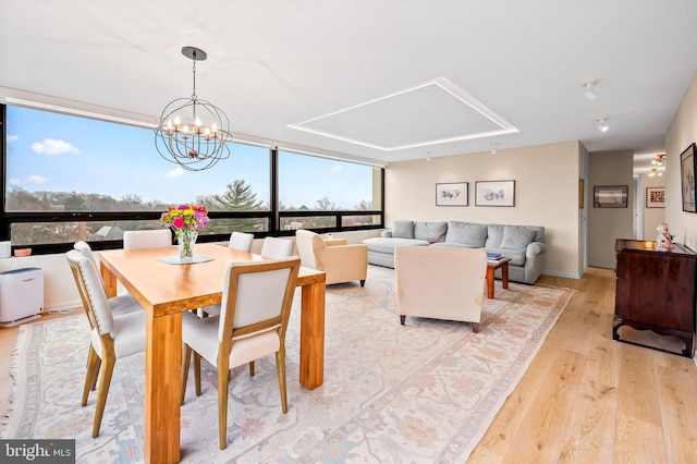 dining room with a notable chandelier, light wood-style floors, and expansive windows