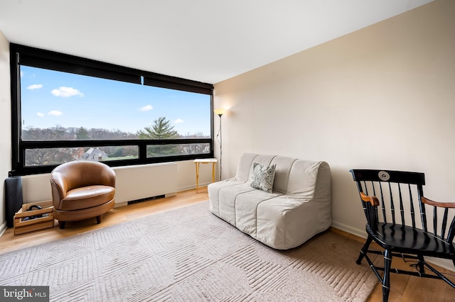 sitting room with baseboards, wood finished floors, and radiator heating unit