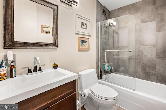 bathroom with combined bath / shower with glass door, toilet, and vanity