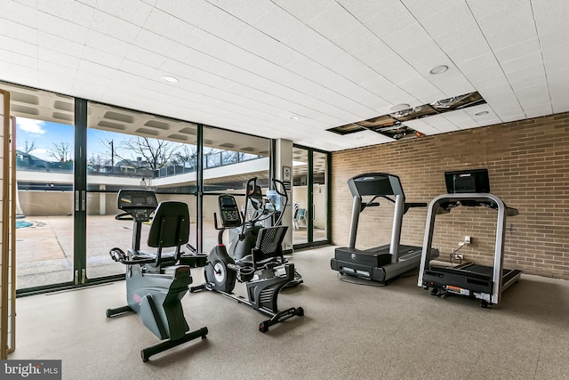 gym featuring brick wall and a wall of windows