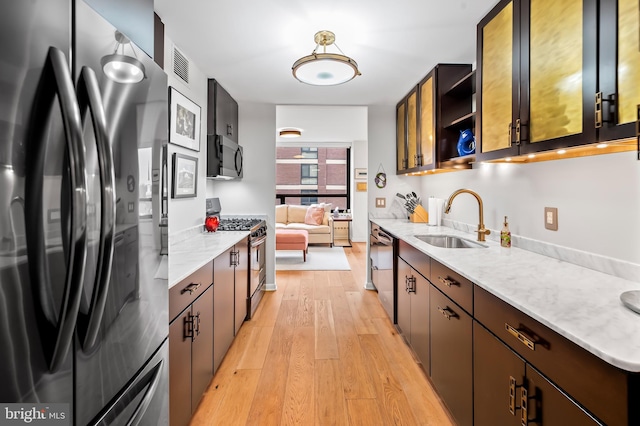 kitchen with visible vents, open shelves, a sink, stainless steel appliances, and light wood-style floors