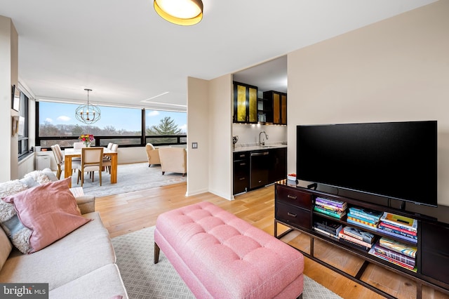 living area featuring a wall of windows, an inviting chandelier, light wood-style flooring, and indoor wet bar