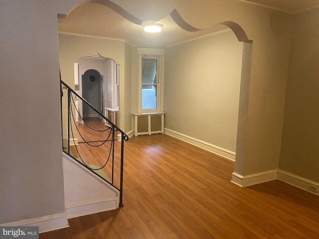 interior space with ornamental molding, radiator heating unit, wood finished floors, and baseboards