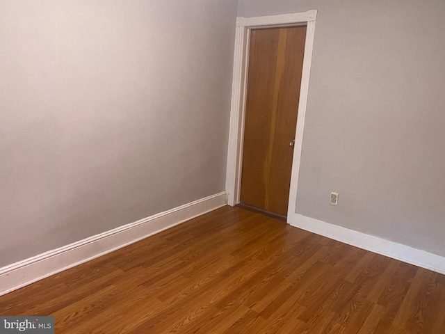 spare room featuring baseboards and dark wood-style flooring