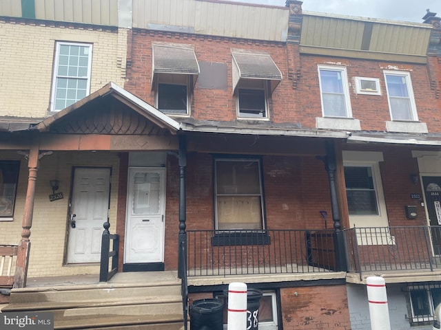 townhome / multi-family property featuring brick siding and a porch