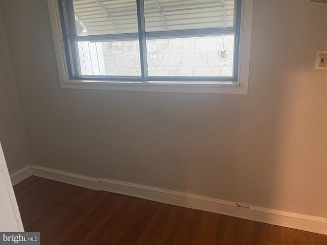 empty room featuring dark wood-style floors, baseboards, and a wealth of natural light