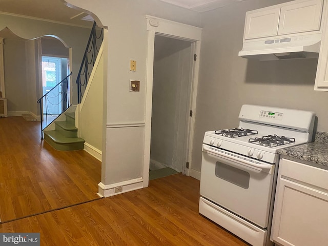 kitchen featuring wood finished floors, white cabinetry, under cabinet range hood, and gas range gas stove